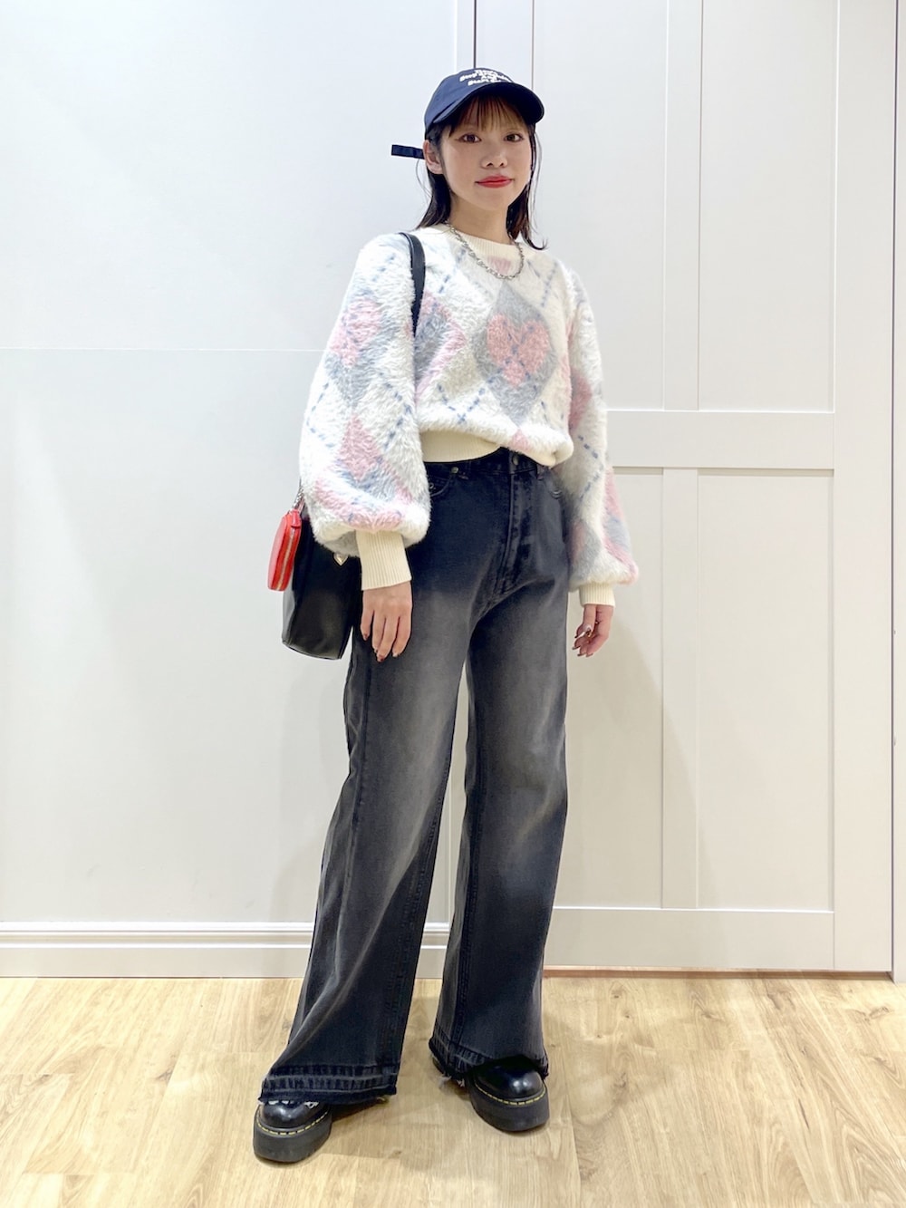 ブラック系のボストンバッグ、ブラック系のデニムパンツ、ホワイト系のニット/セーターを着用したレディースの秋コーディネートの2枚目の写真