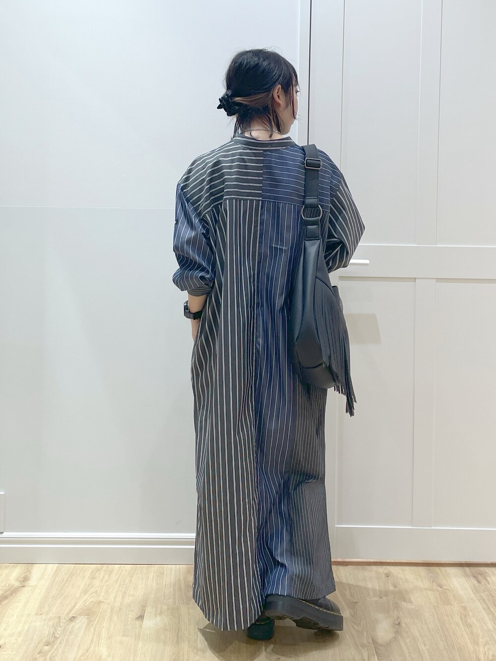ブルー系のワンピース、ブラック系のショルダーバッグ、ブラック系のブーツを着用したレディースの春コーディネートの2枚目の写真