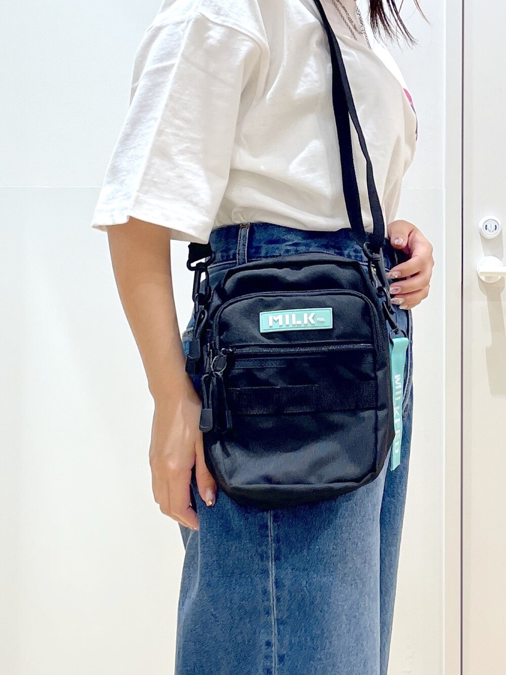 グリーン系のショルダーバッグ、ブラック系のサンダル、ホワイト系のTシャツ/カットソーを着用したレディースの夏コーディネートの4枚目の写真