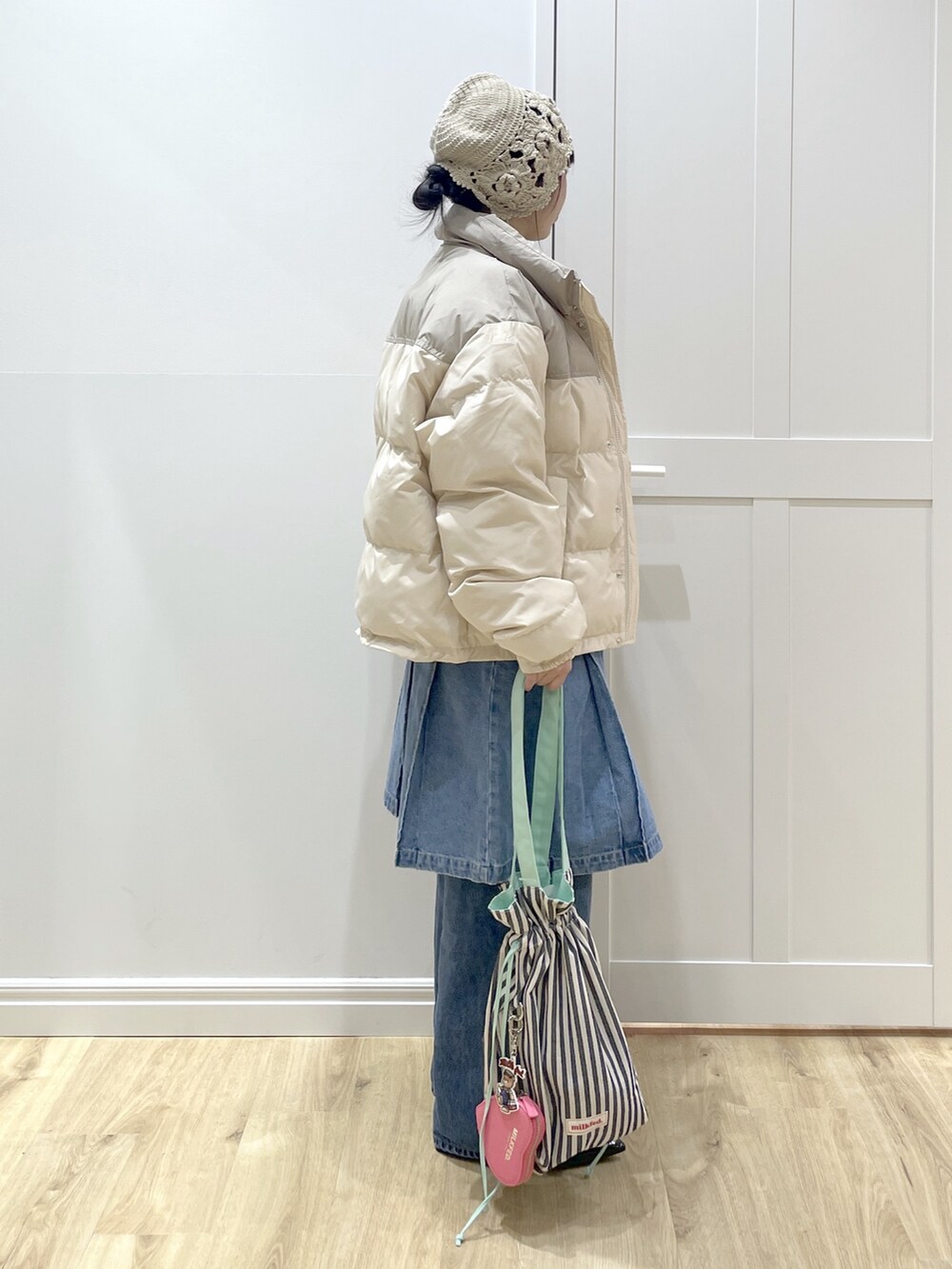 ホワイト系のダウンジャケット/コート、ベージュ系のTシャツ/カットソー、ブルー系のデニムパンツを着用したレディースの冬コーディネートの2枚目の写真