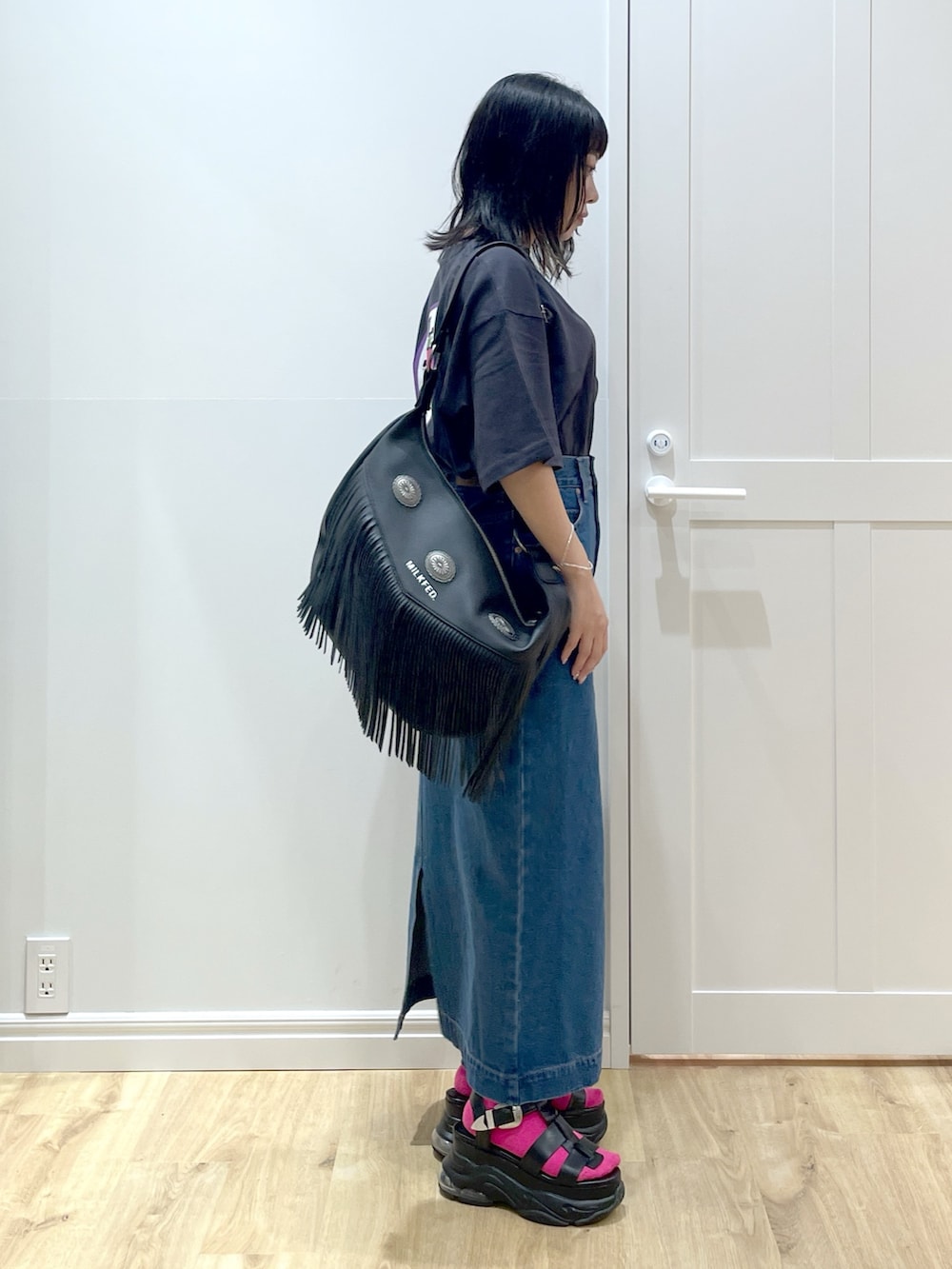 ブラック系のショルダーバッグ、グレー系のTシャツ/カットソー、ブルー系のデニムスカートを着用したレディースの夏コーディネートの3枚目の写真