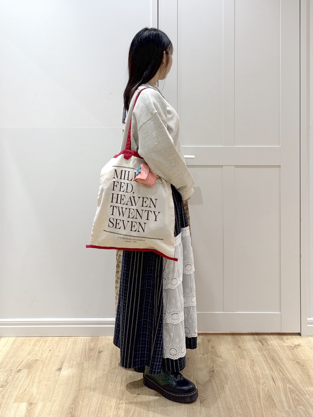 ホワイト系のトートバッグ、ベージュ系のスウェット、ベージュ系のスカートを着用したレディースの冬コーディネートの2枚目の写真