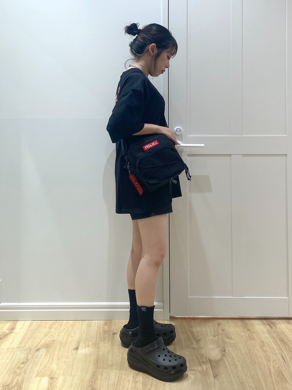 レッド系のショルダーバッグ、ブラック系のデニムパンツ、ブラック系のTシャツ/カットソーを着用したレディースの夏コーディネートの2枚目の写真