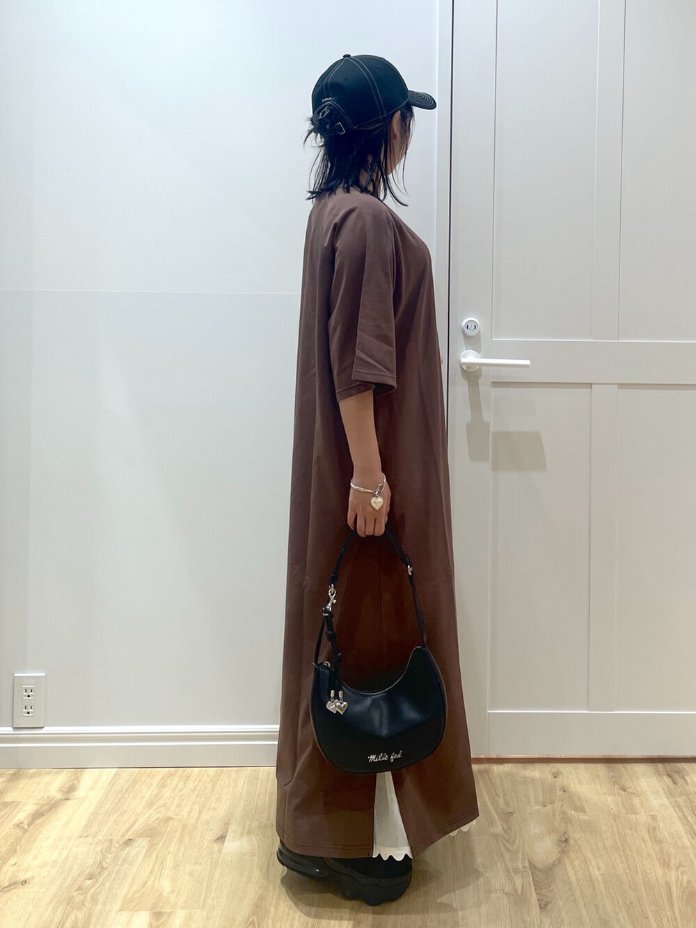 ブラック系のサンダル、ブラック系のハンドバッグ、ホワイト系のスカートを着用したレディースの春コーディネートの2枚目の写真