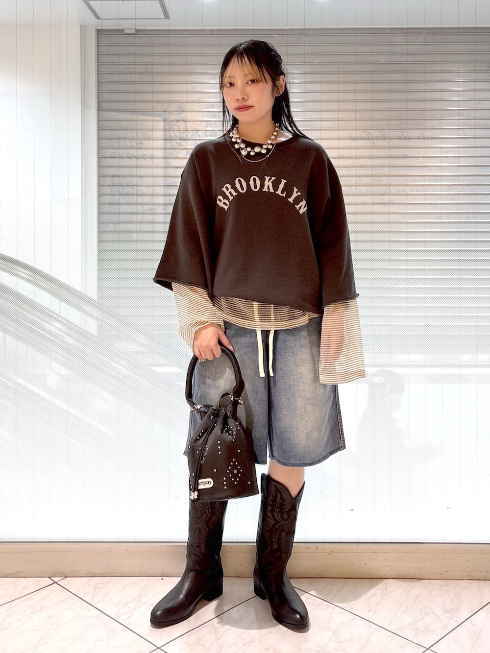 ブラック系のブーツ、ブラック系のショルダーバッグ、ブルー系のその他パンツを着用したレディースの春コーディネートの4枚目の写真