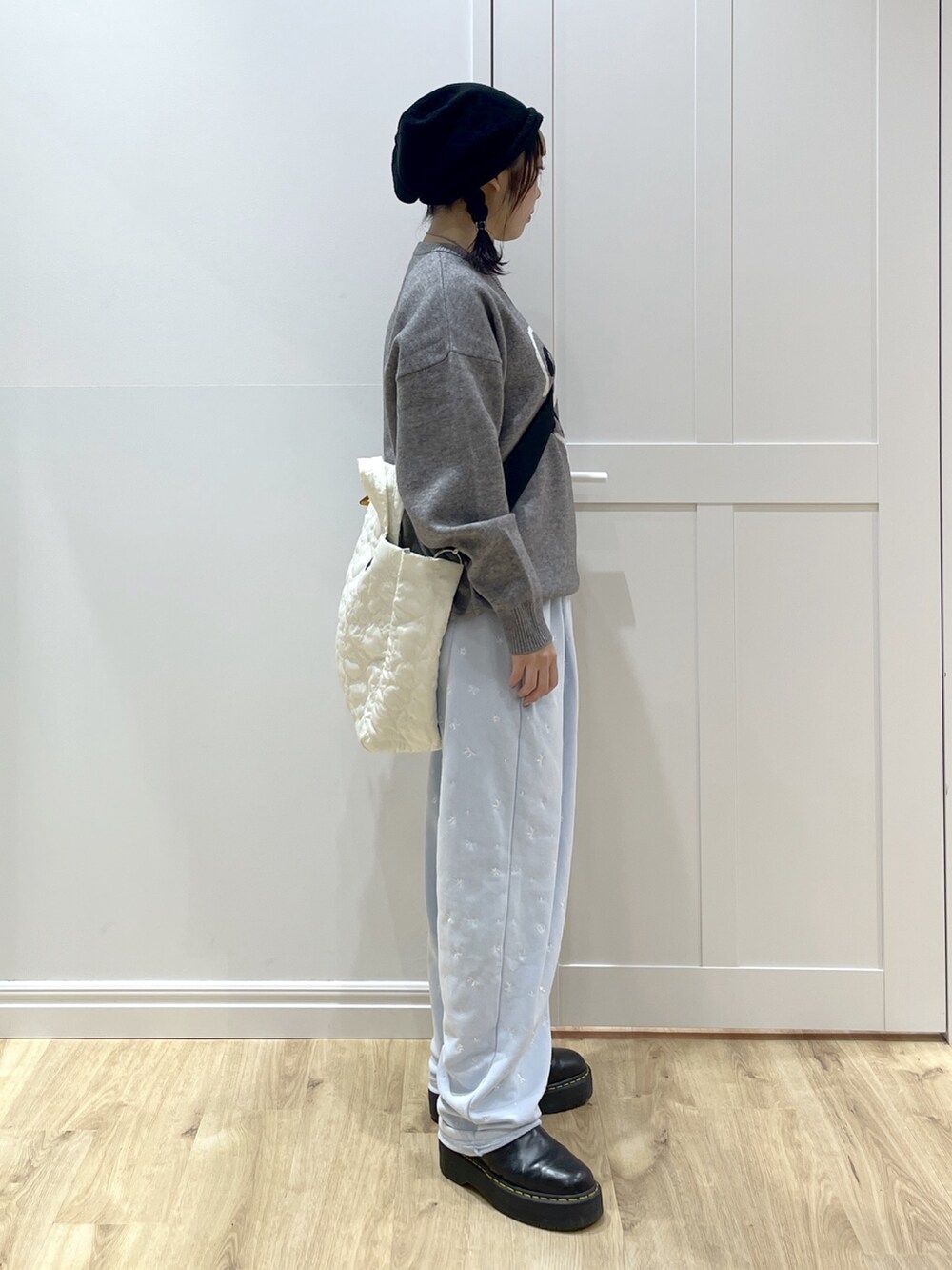 ブルー系のスウェットパンツ、グレー系のニット/セーター、ホワイト系のショルダーバッグを着用したレディースの秋コーディネートの3枚目の写真