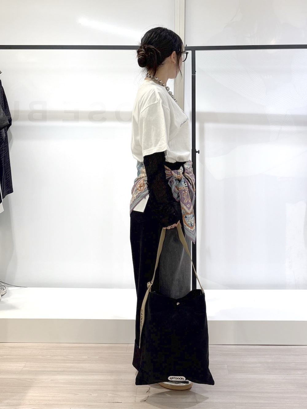 ブラック系のデニムパンツ、シルバー系のスニーカー、ホワイト系のTシャツ/カットソーを着用したレディースの春コーディネートの5枚目の写真