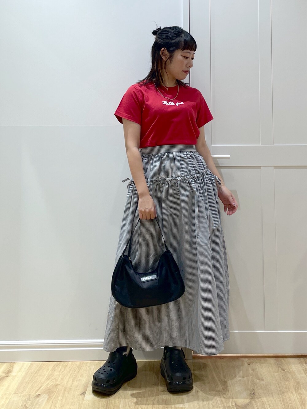 ブラック系のスカート、ブラック系のハンドバッグ、レッド系のTシャツ/カットソーを着用したレディースの夏コーディネートの2枚目の写真