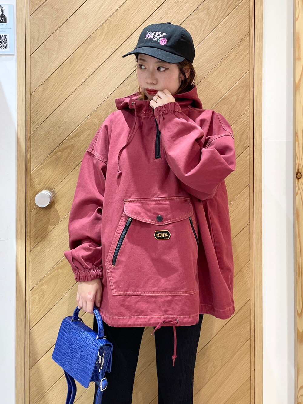 ブルー系のショルダーバッグ、ブラック系のブーツ、レッド系のブルゾンを着用したレディースの秋コーディネートの2枚目の写真