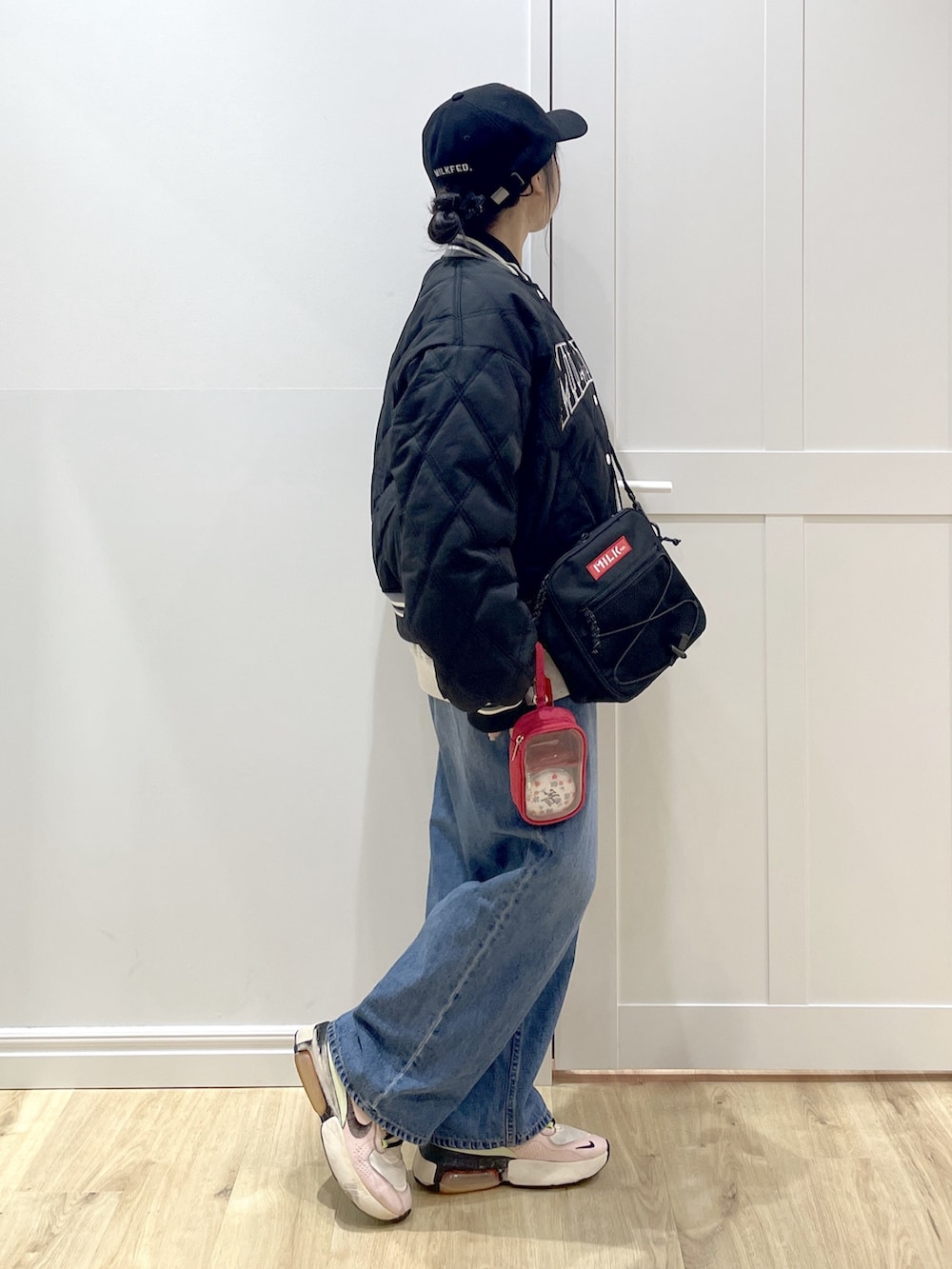 ブルー系のデニムパンツ、ベージュ系のスウェット、レッド系のショルダーバッグを着用したレディースの冬コーディネートの4枚目の写真