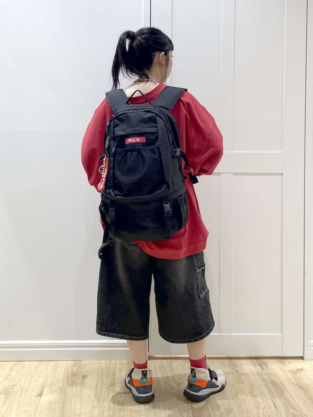 レッド系のバックパック/リュック、ブラック系のデニムパンツ、レッド系のTシャツ/カットソーを着用したレディースの秋コーディネートの3枚目の写真