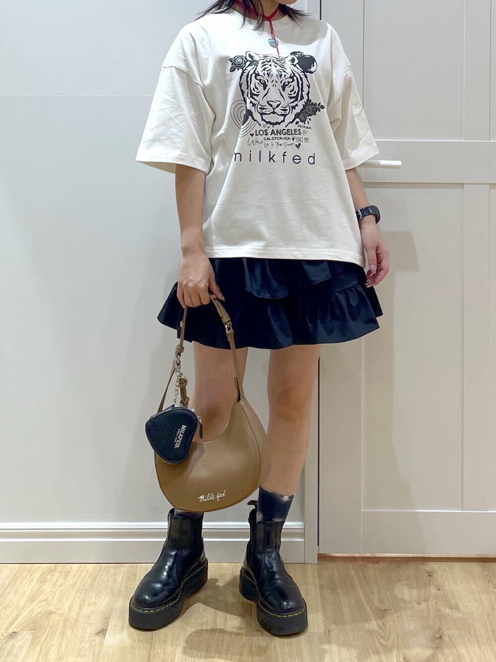 ブラック系のスカート、ホワイト系のTシャツ/カットソー、ブラック系のブーツを着用したレディースの夏コーディネートの5枚目の写真