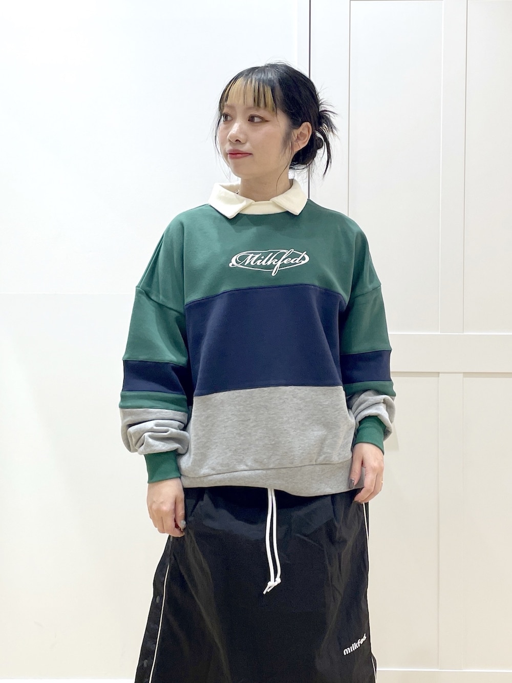 グリーン系のスウェット、ブラック系のスカート、ブルー系のトートバッグを着用したレディースの冬コーディネートの7枚目の写真