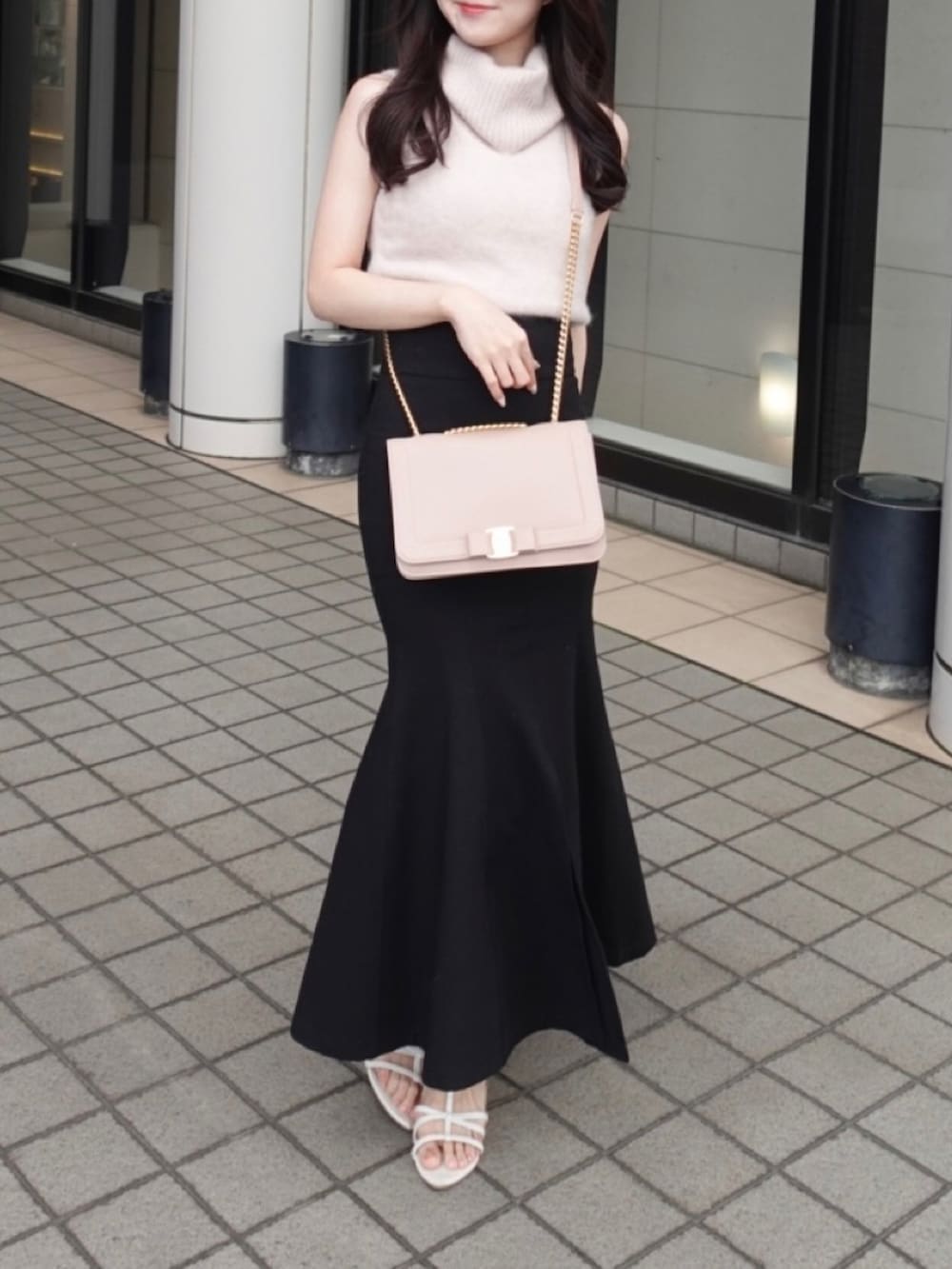 ピンク系のバッグ、ピンク系のニット/セーター、ブラック系のスカートを着用したレディースの秋コーディネートの2枚目の写真