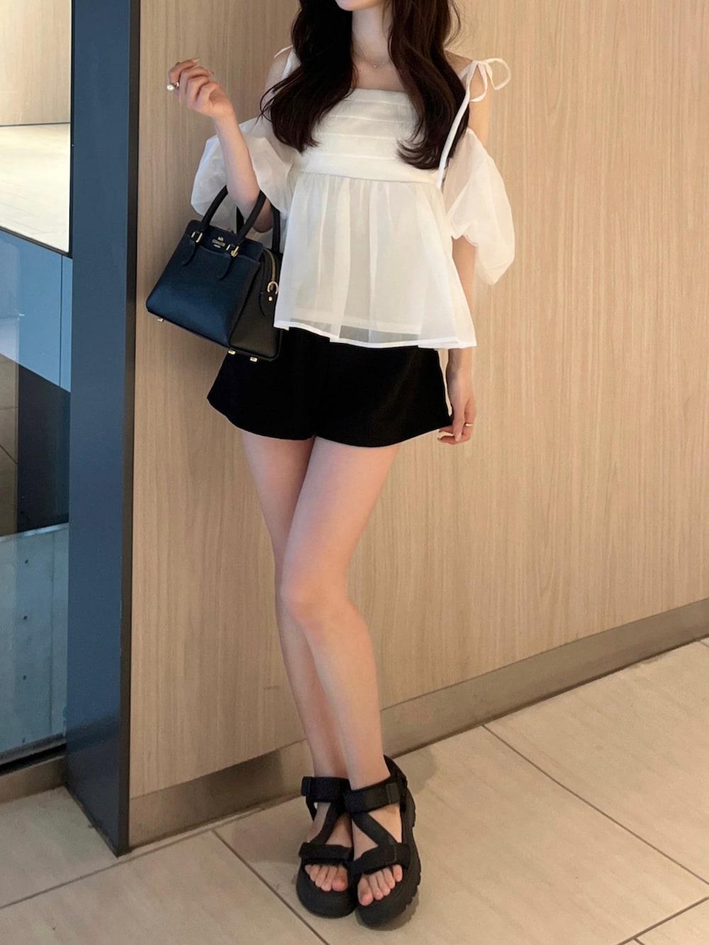 ブラック系のパンツ、ホワイト系のシャツ/ブラウス、ブラック系のバッグを着用したレディースの夏コーディネートの3枚目の写真
