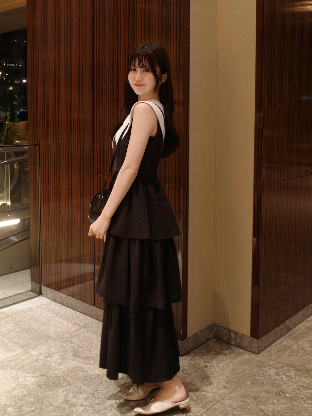 ブラック系のショルダーバッグ、ホワイト系のサンダル、ブラック系のワンピース/ドレスを着用したレディースの夏コーディネートの2枚目の写真