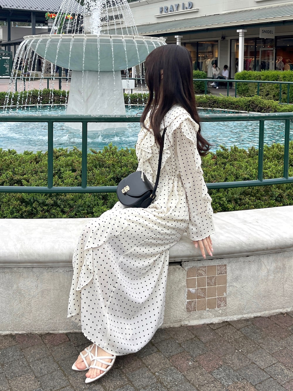 ブラック系のショルダーバッグ、ホワイト系のサンダル、その他のワンピースを着用したレディースの春コーディネートの2枚目の写真