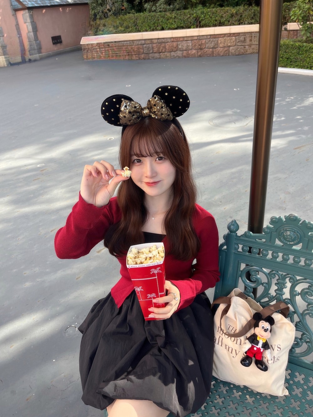レッド系のトップス、ブラック系のスカート、ホワイト系のトートバッグを着用したレディースの秋コーディネートの5枚目の写真