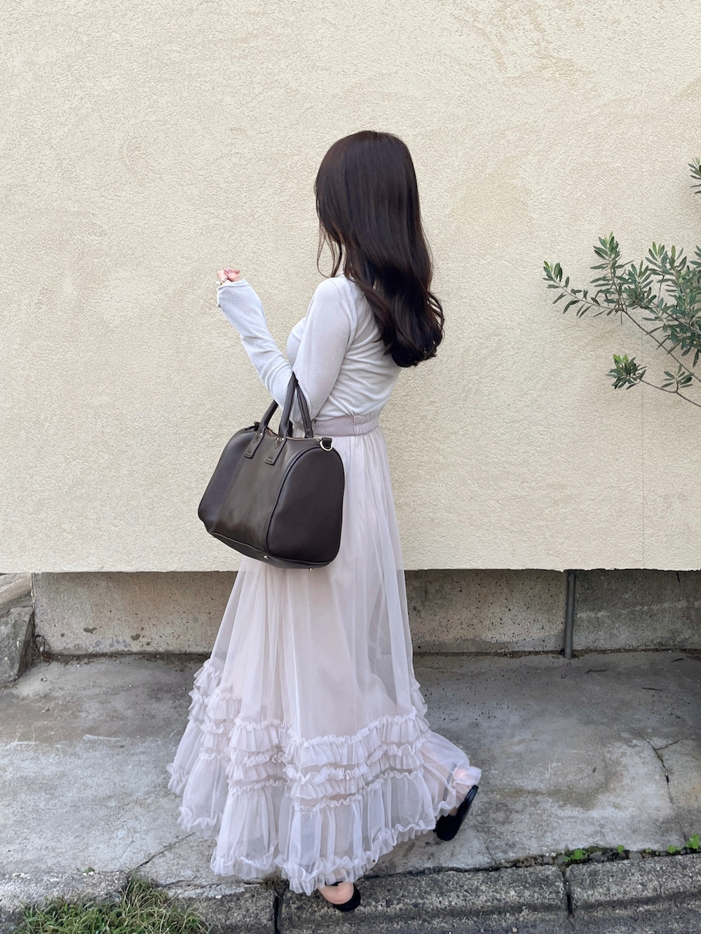 ブラウン系のボストンバッグ、ピンク系のスカート、ホワイト系のニット/セーターを着用したレディースの秋コーディネートの2枚目の写真