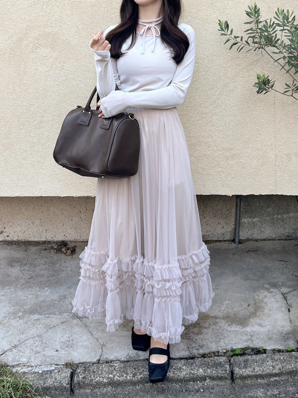 ブラウン系のボストンバッグ、ピンク系のスカート、ホワイト系のニット/セーターを着用したレディースの秋コーディネートの3枚目の写真