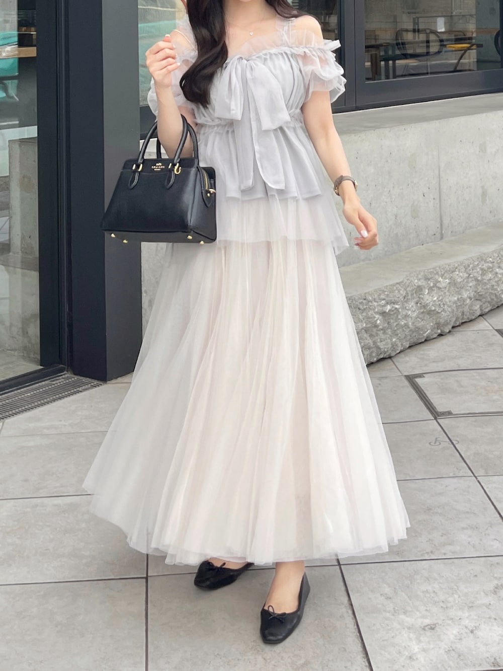 グレー系のシャツ/ブラウス、ブラック系のバッグ、ホワイト系のスカートを着用したレディースの夏コーディネートの3枚目の写真