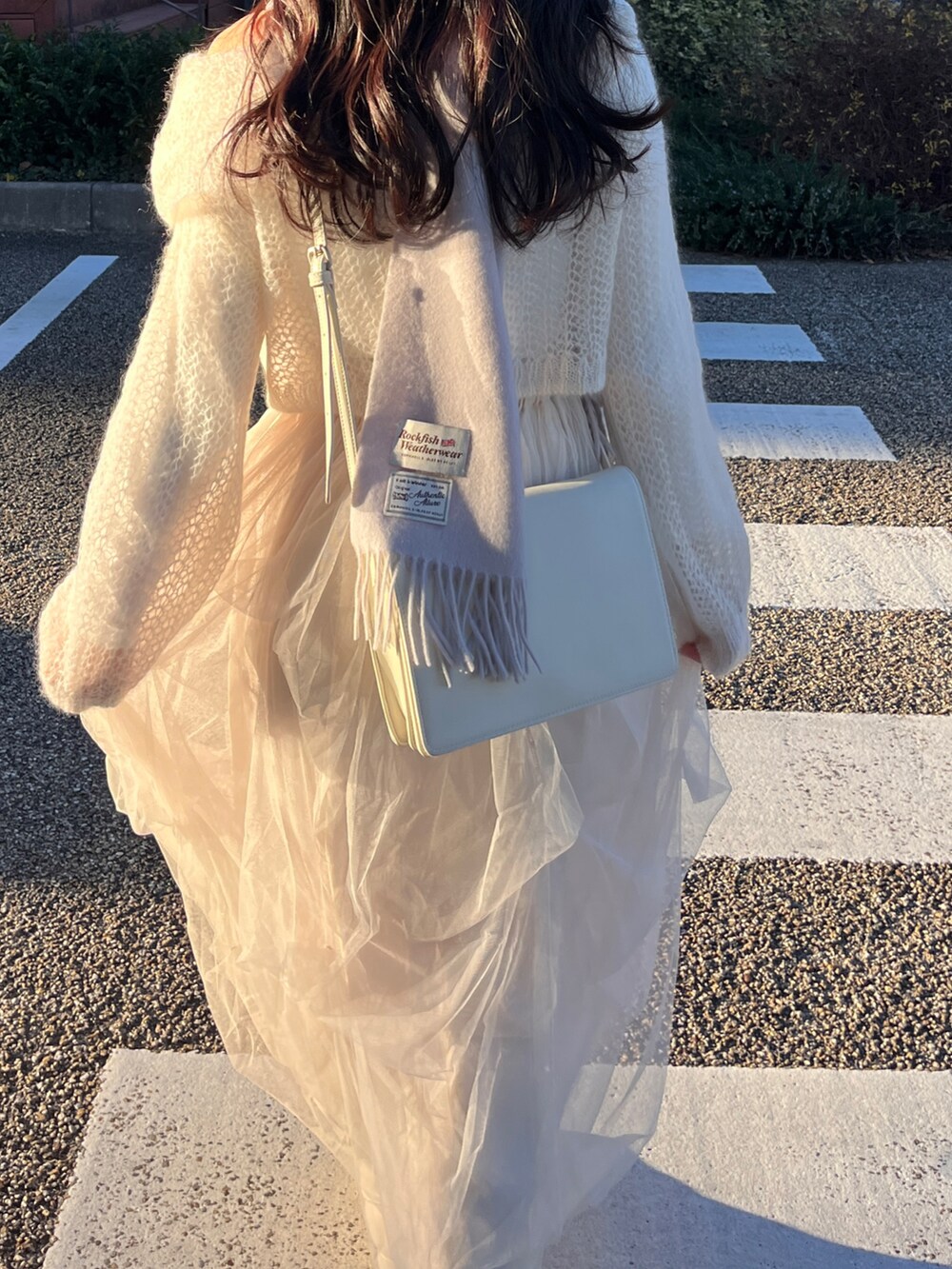 ホワイト系のニット/セーター、ホワイト系のスカート、ホワイト系のショルダーバッグを着用したレディースの冬コーディネートの5枚目の写真