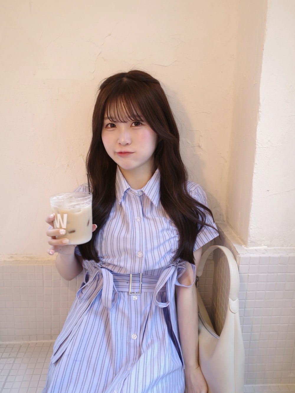 ブルー系のワンピース、ホワイト系のバッグ、ブラック系のブーツを着用したレディースの春コーディネートの2枚目の写真