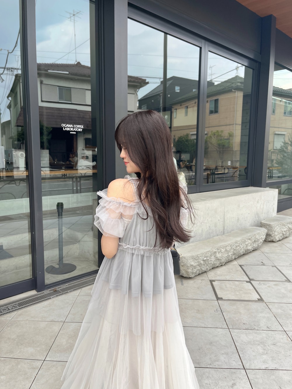 グレー系のシャツ/ブラウス、ブラック系のバッグ、ホワイト系のスカートを着用したレディースの夏コーディネートの2枚目の写真