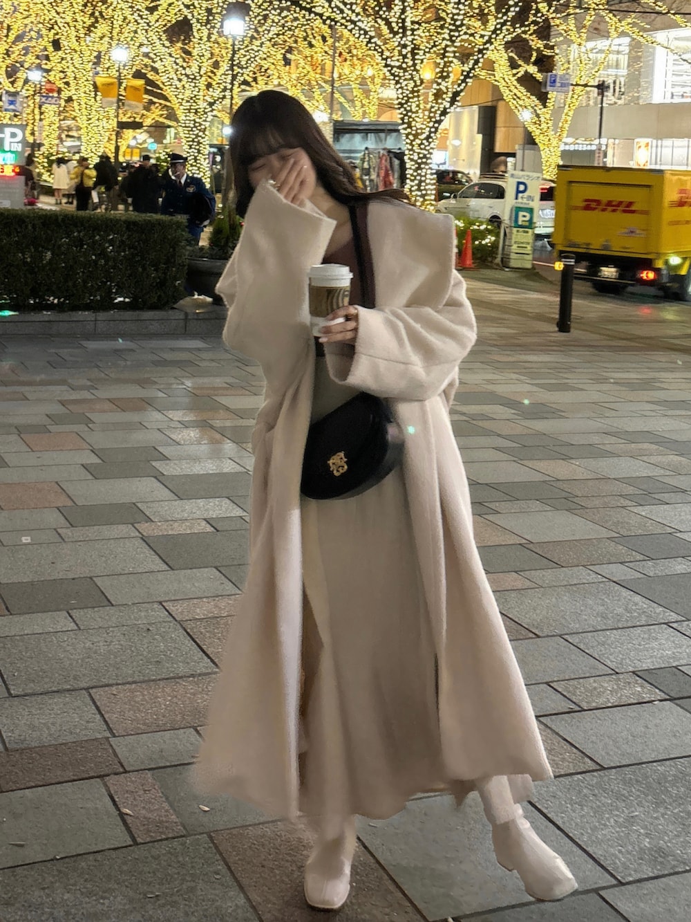 ホワイト系のチェスターコート、ブラック系のショルダーバッグ、ピンク系のニット/セーターを着用したレディースの冬コーディネートの2枚目の写真