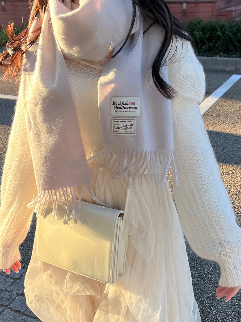 ホワイト系のニット/セーター、ホワイト系のスカート、ホワイト系のショルダーバッグを着用したレディースの冬コーディネートの4枚目の写真