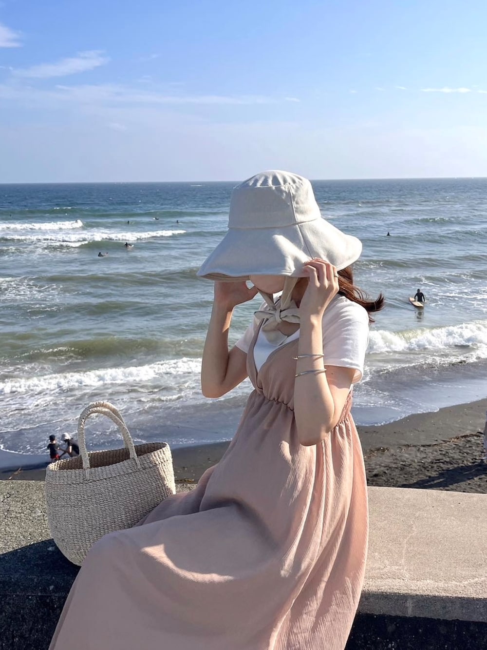 ピンク系のワンピース/ドレス、ベージュ系のバッグ、ホワイト系のハットを着用したレディースの夏コーディネートの3枚目の写真