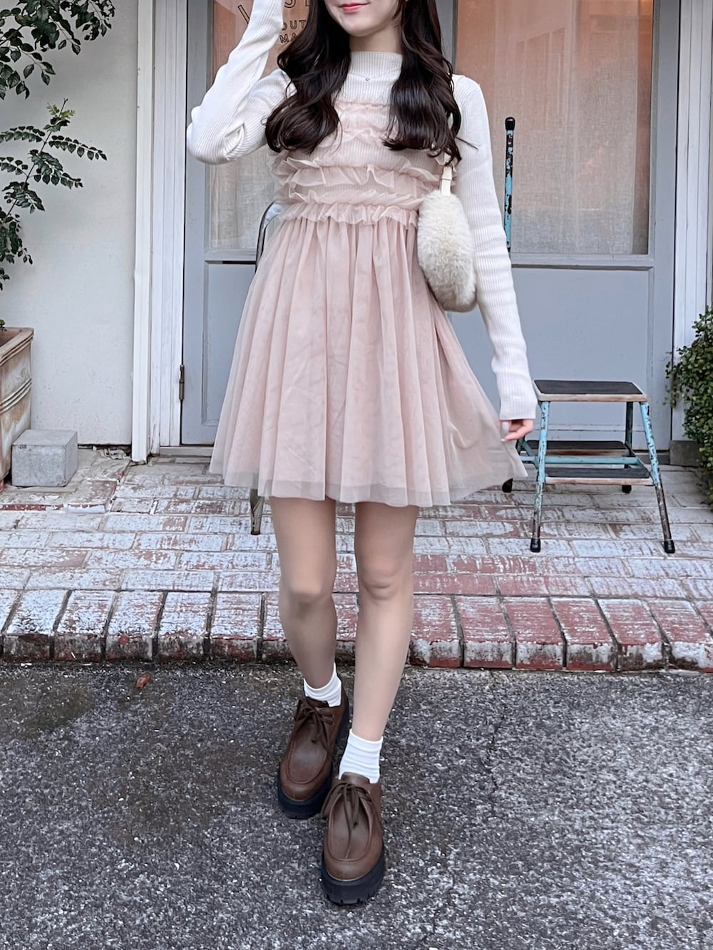 ピンク系のワンピース、ブラウン系のローファー、ベージュ系のハンドバッグを着用したレディースの冬コーディネートの2枚目の写真