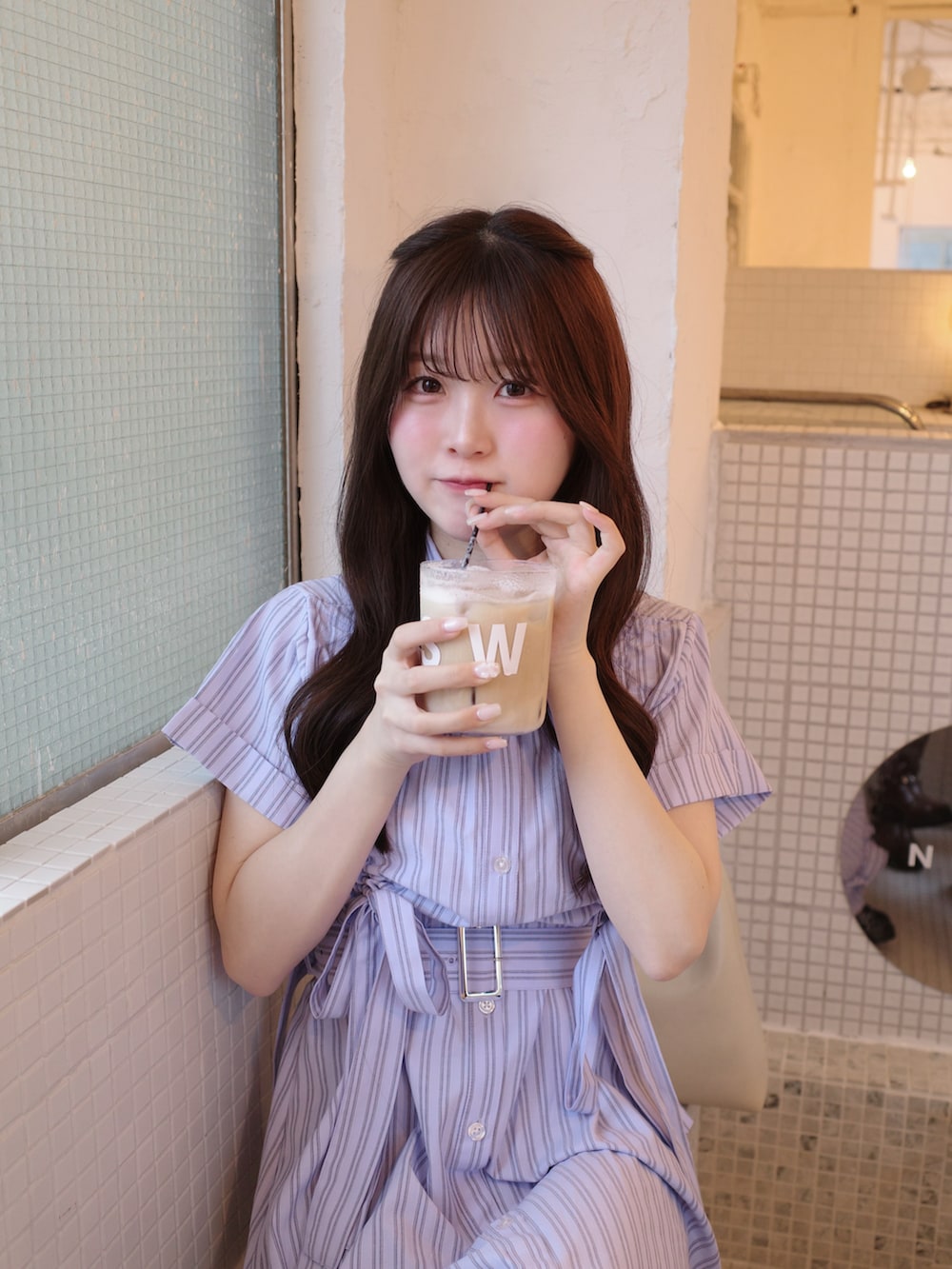 ブルー系のワンピース、ホワイト系のバッグ、ブラック系のブーツを着用したレディースの春コーディネートの3枚目の写真