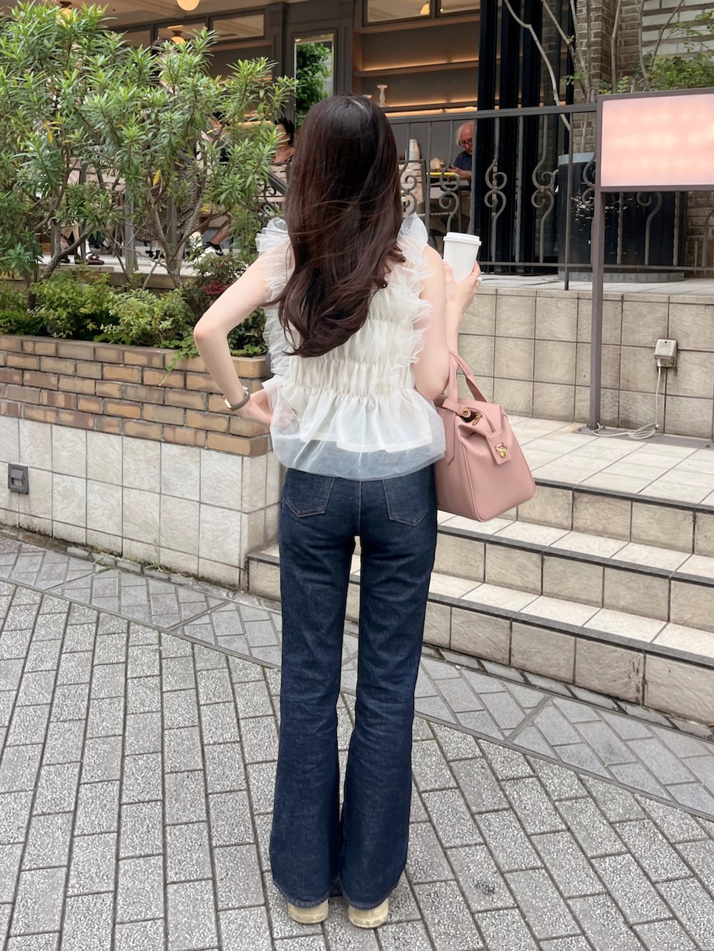 ホワイト系のトップス、ピンク系のバッグ、ブルー系のデニムパンツを着用したレディースの夏コーディネートの2枚目の写真