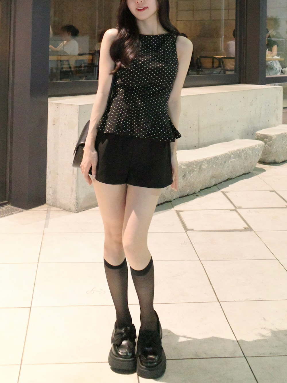 ブラック系のトップス、ブラック系のローファーを着用したレディースの夏コーディネートの2枚目の写真