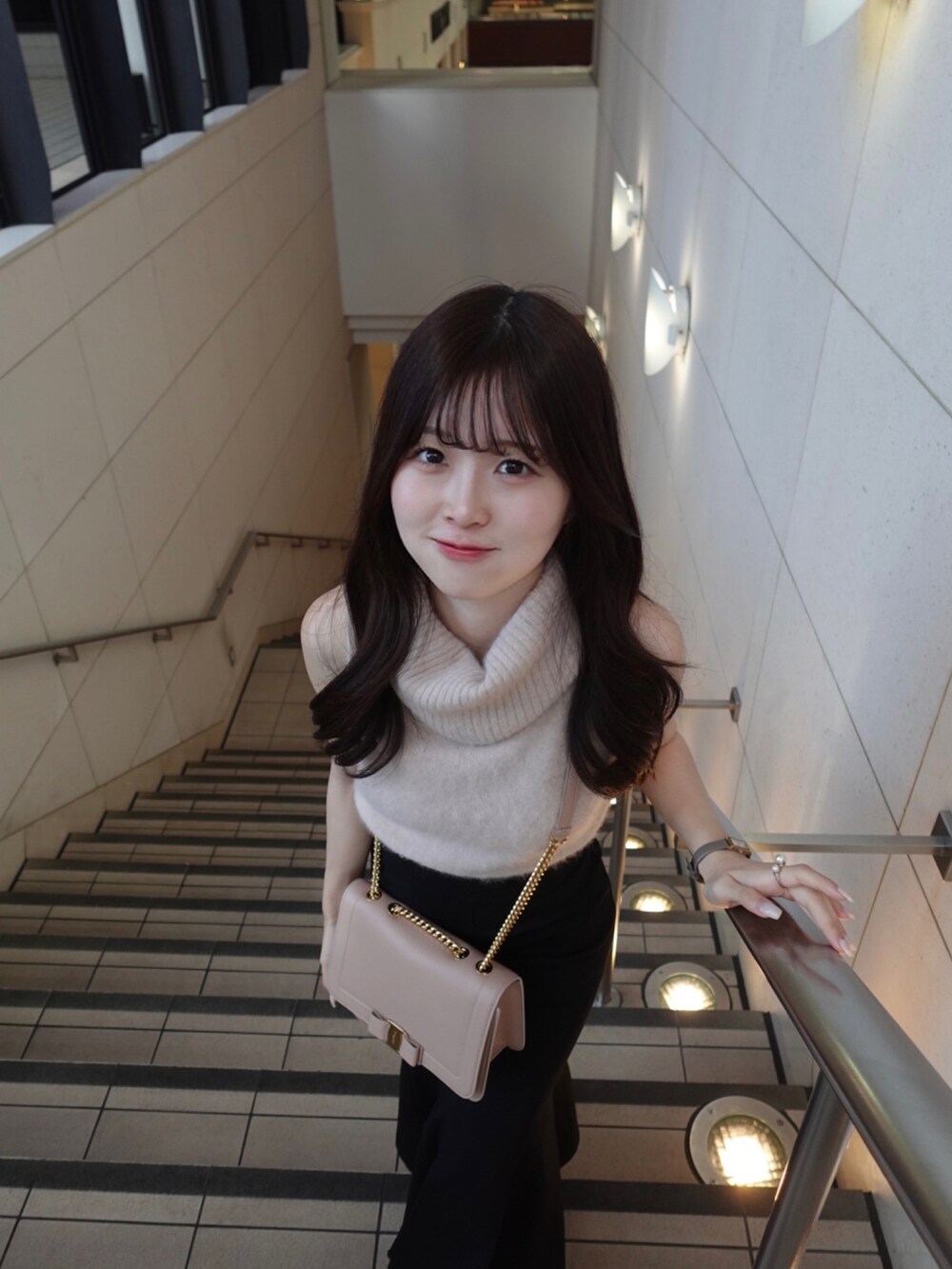 ピンク系のバッグ、ピンク系のニット/セーター、ブラック系のスカートを着用したレディースの秋コーディネートの3枚目の写真