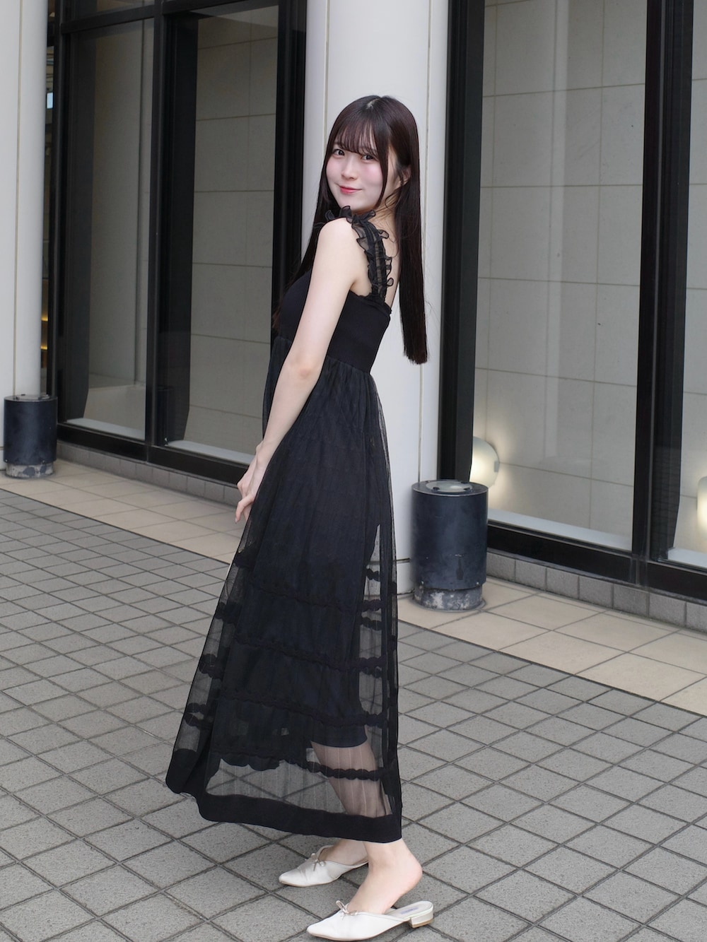 ホワイト系のサンダル、ブラック系のワンピース、ベージュ系のバッグを着用したレディースの夏コーディネートの2枚目の写真