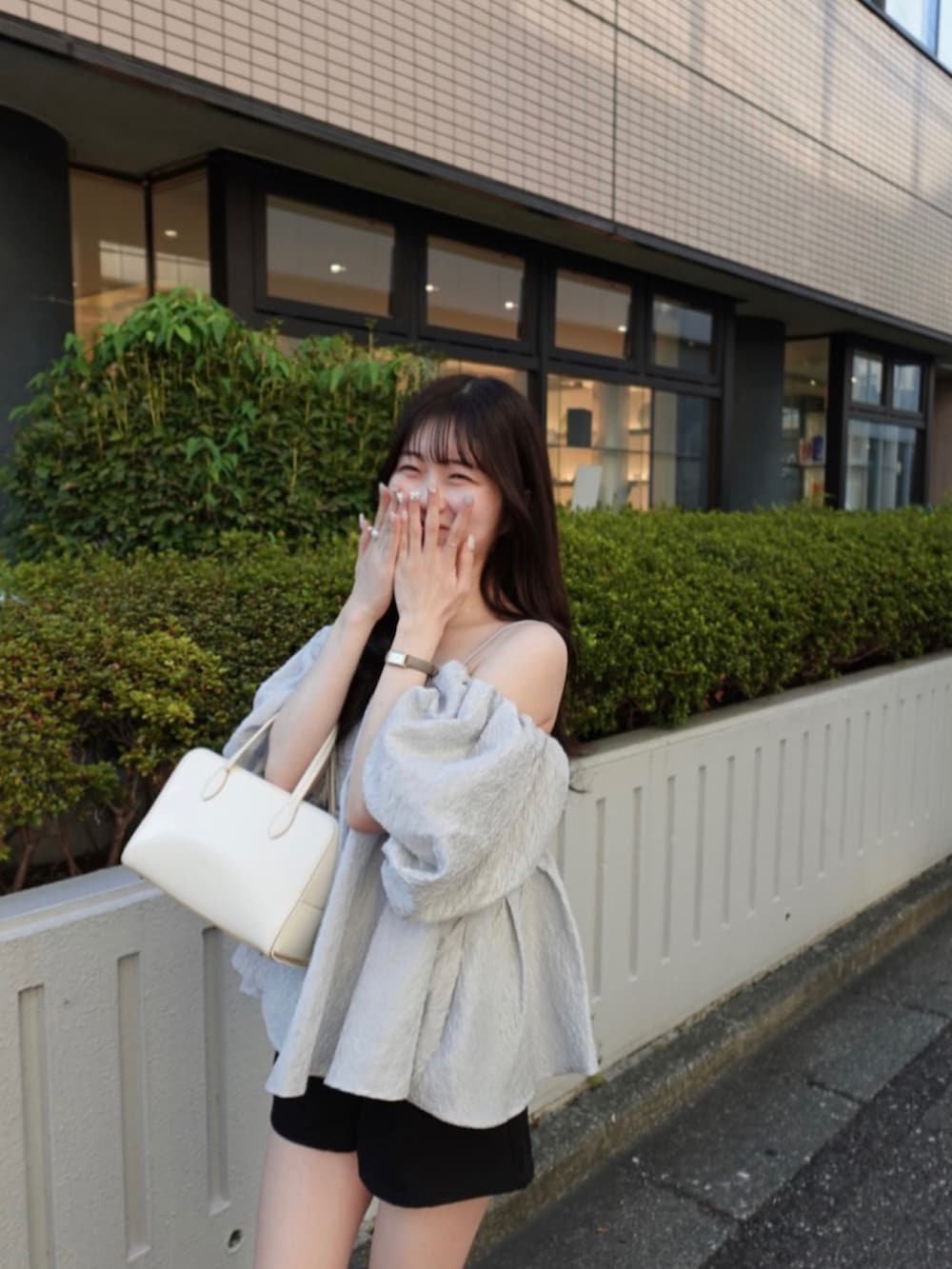 グレー系のベスト、ブラック系のパンツ、ホワイト系のバッグを着用したレディースの夏コーディネートの3枚目の写真