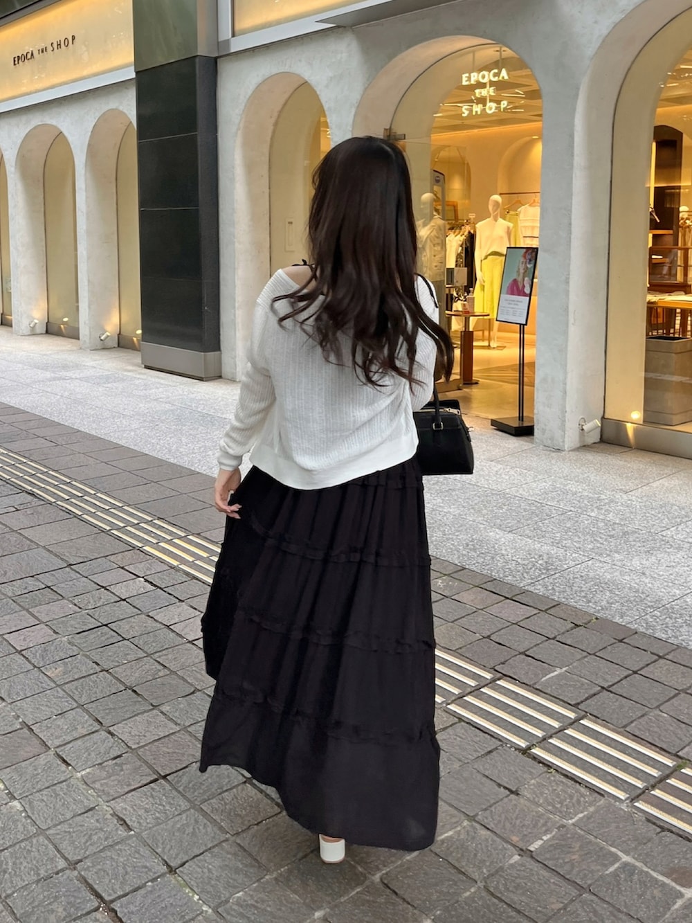 ブラック系のワンピース/ドレス、ブラック系のバッグ、ホワイト系のサンダルを着用したレディースの夏コーディネートの2枚目の写真