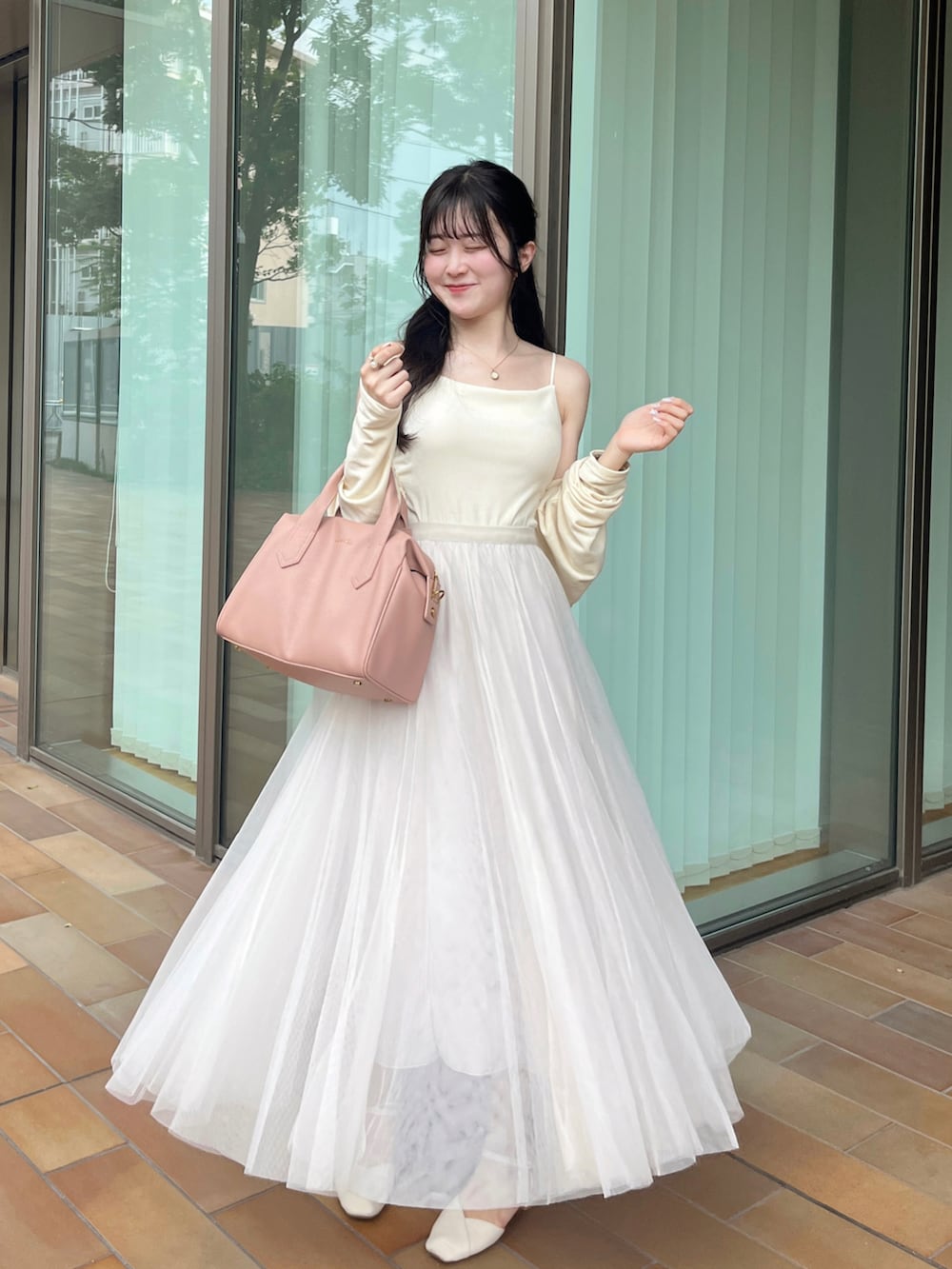 ピンク系のバッグ、ホワイト系のスカート、ホワイト系のキャミソールを着用したレディースの夏コーディネートの2枚目の写真