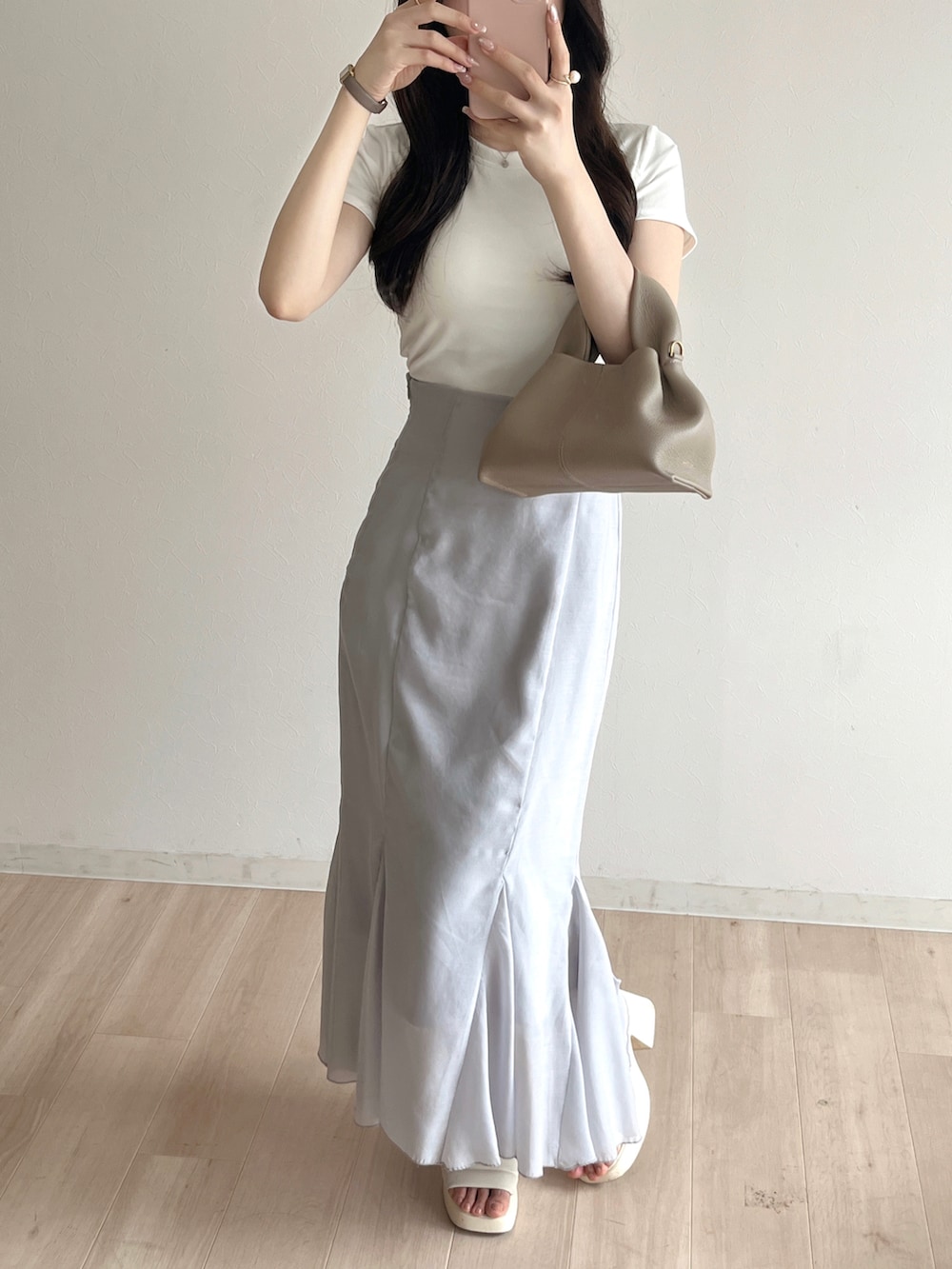 グレー系のスカート、ホワイト系のTシャツ/カットソー、ベージュ系のバッグを着用したレディースの夏コーディネートの2枚目の写真
