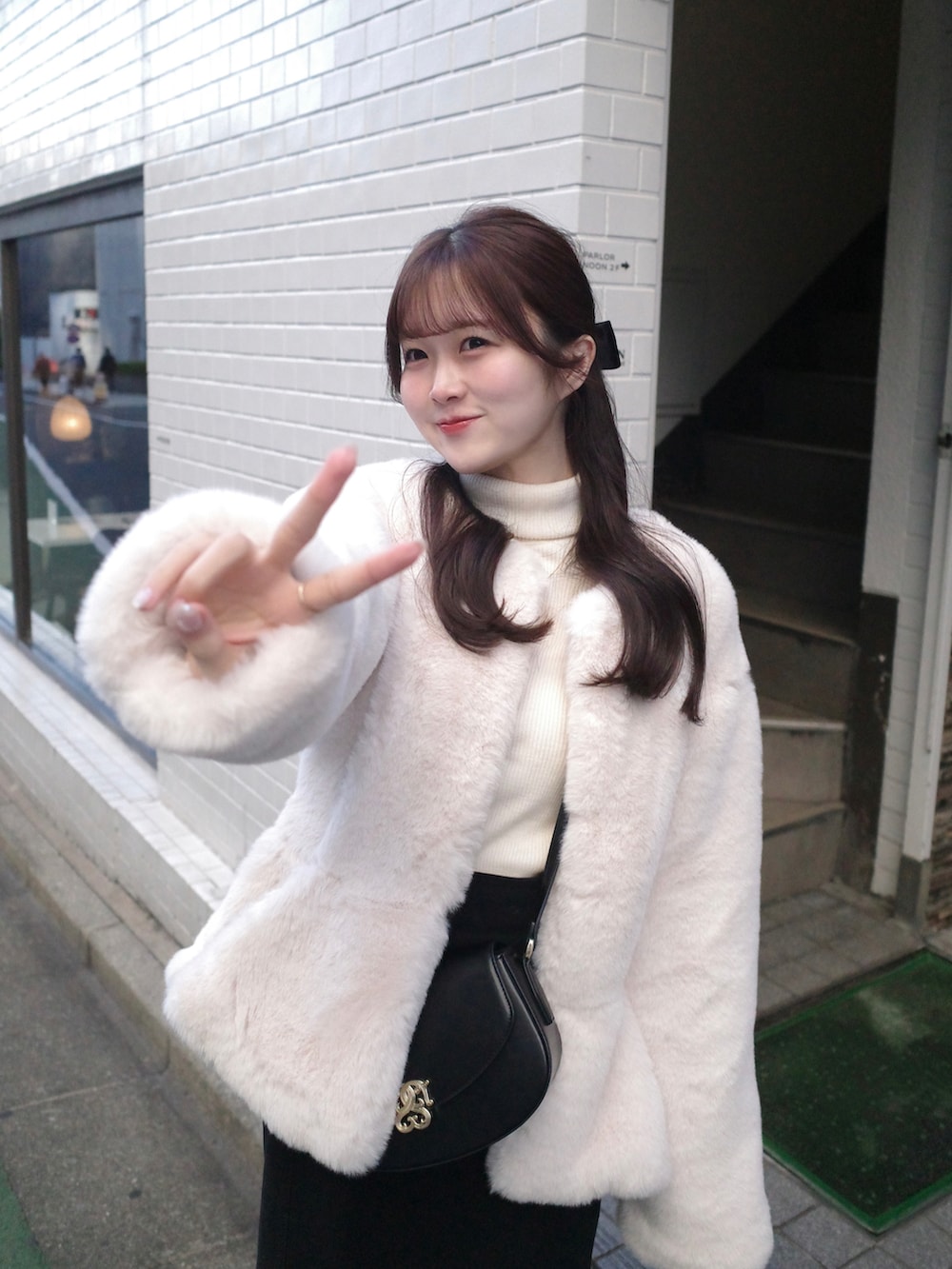 ホワイト系のノーカラーコート、ブラック系のショルダーバッグ、ホワイト系のニット/セーターを着用したレディースの秋コーディネートの2枚目の写真