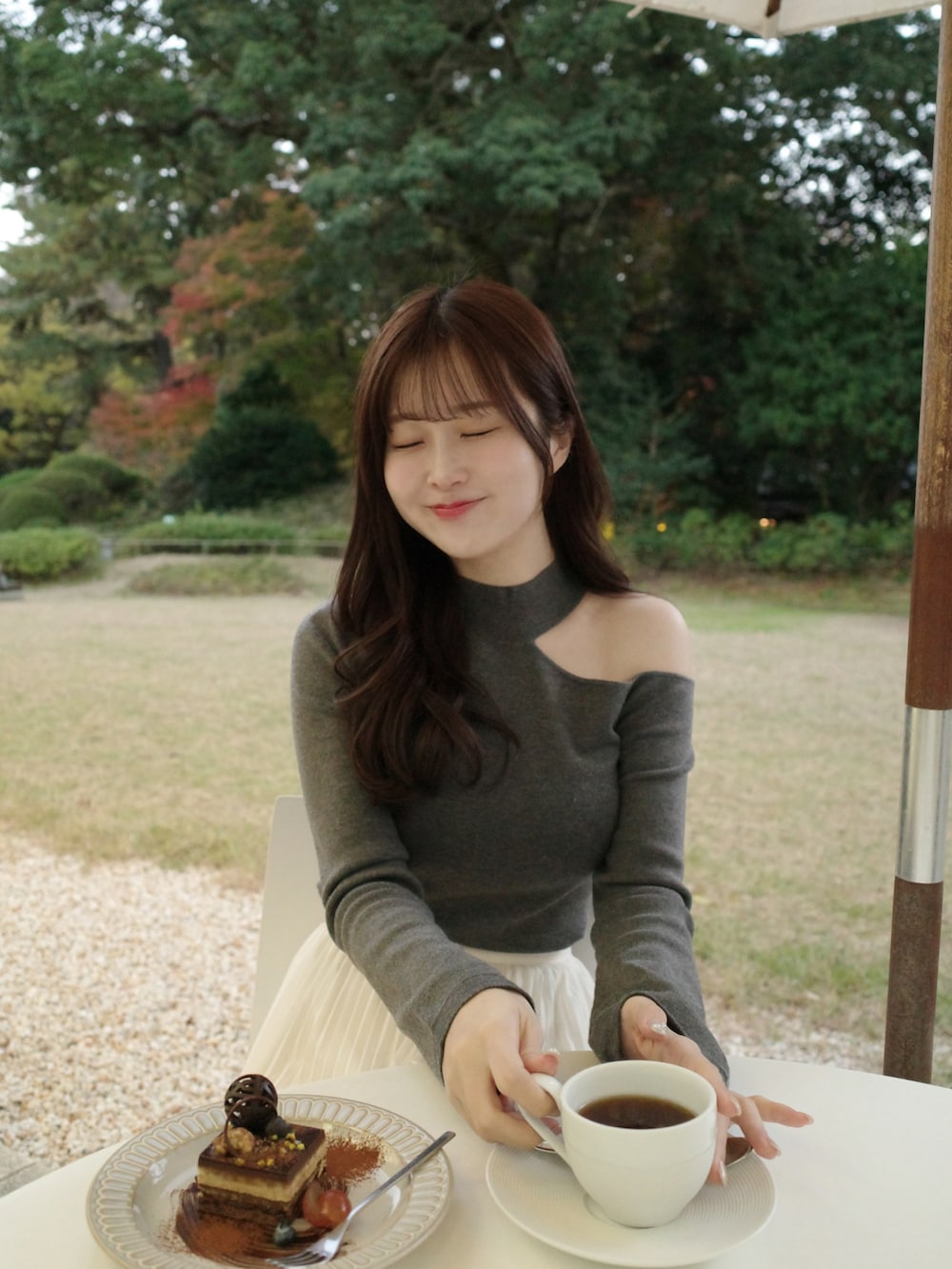 グレー系のニット/セーター、ベージュ系のチェスターコート、ホワイト系のスカートを着用したレディースの冬コーディネートの2枚目の写真