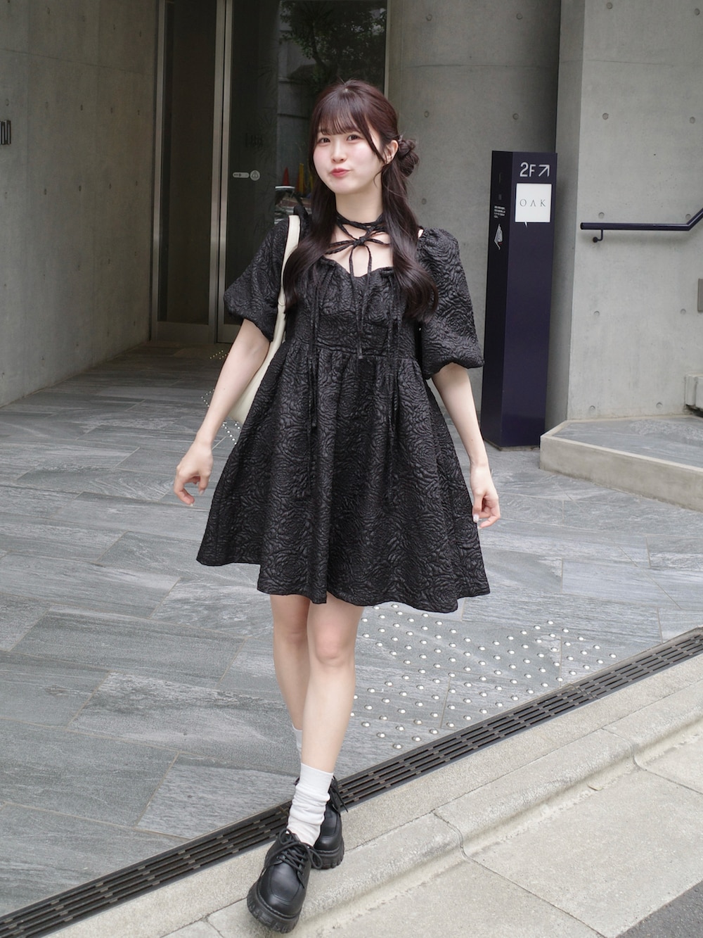 ブラック系のワンピース、ホワイト系のバッグを着用したレディースの春コーディネートの2枚目の写真