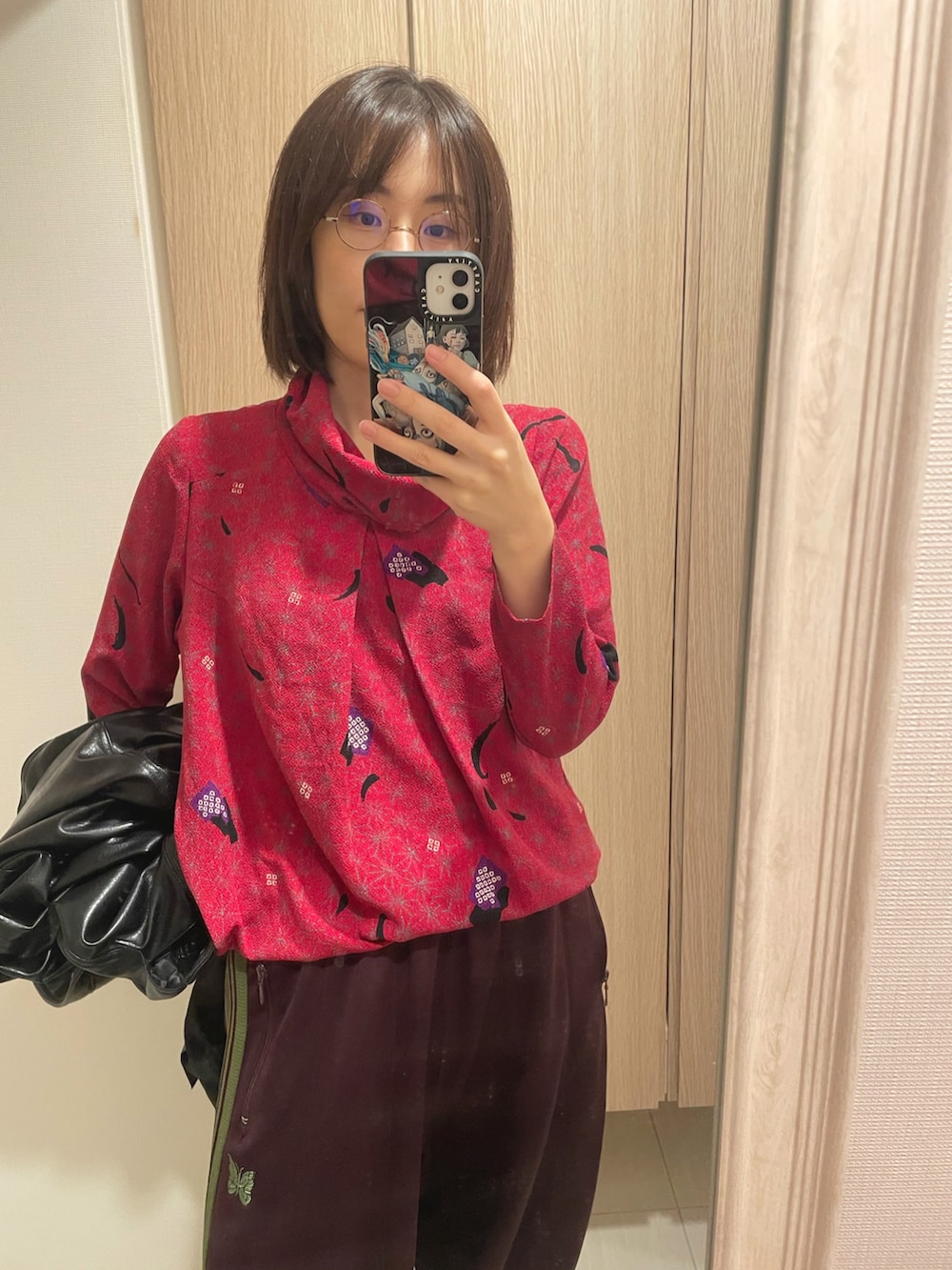 ブラック系のスニーカー、レッド系のトップス、ブラック系のブルゾンを着用したレディースの秋コーディネートの2枚目の写真