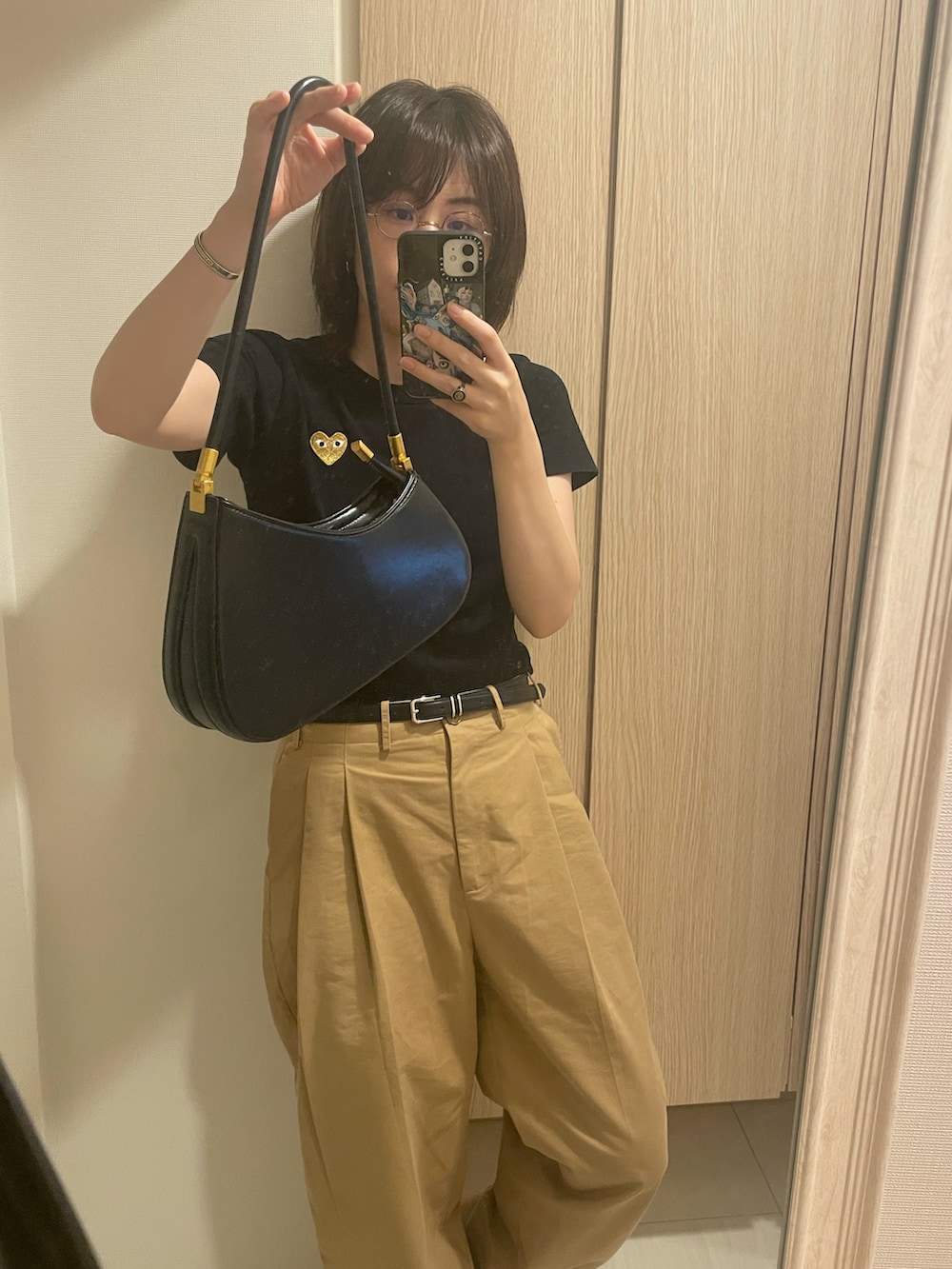 ベージュ系のチノパンツ、ブラック系のハンドバッグ、ブラック系のTシャツ/カットソーを着用したレディースの秋コーディネートの2枚目の写真