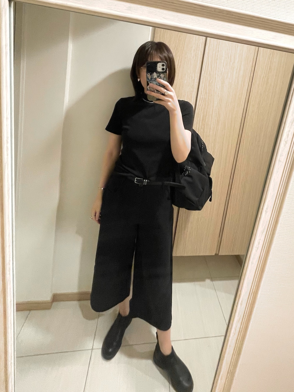 ブラック系のデニムパンツ、ブラック系のTシャツ/カットソー、ブラック系のブーツを着用したレディースの秋コーディネートの2枚目の写真