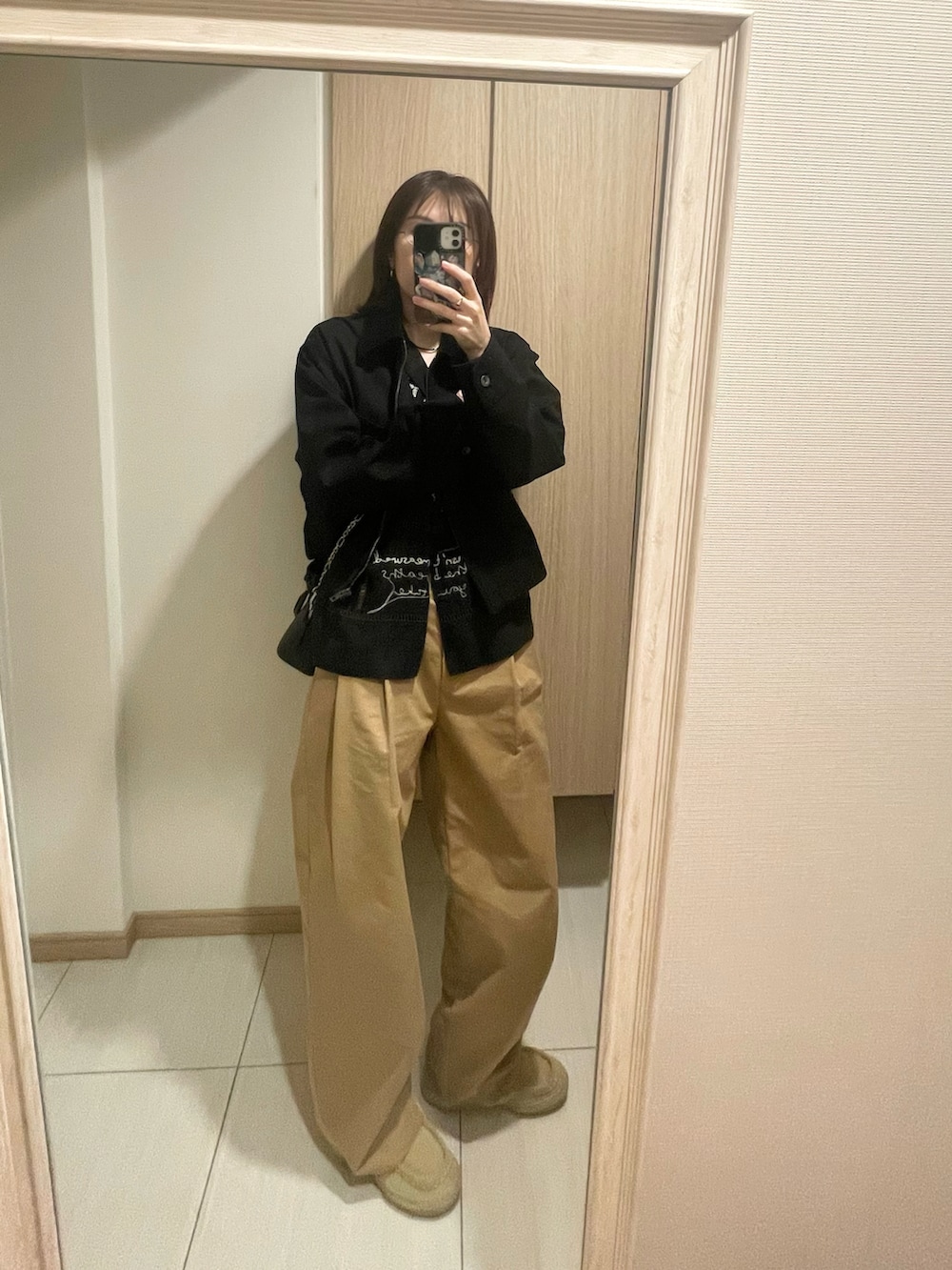 ブラック系のシャツ/ブラウス、ベージュ系のチノパンツ、シルバー系のネックレスを着用したレディースの春コーディネートの3枚目の写真