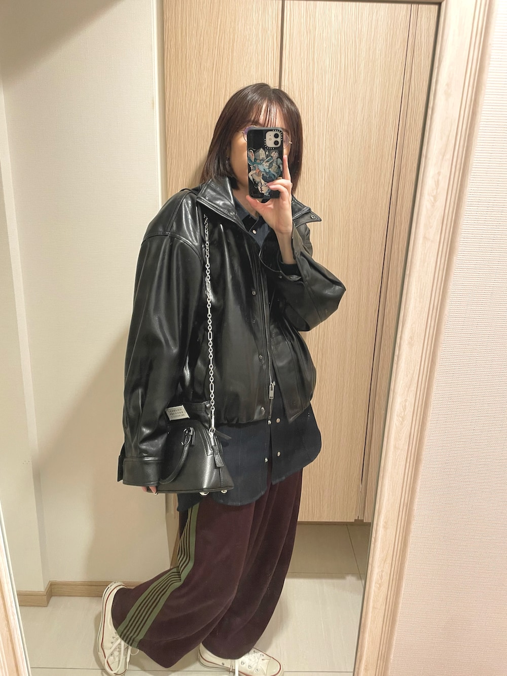 ブラック系のショルダーバッグ、ホワイト系のスニーカー、ブルー系のトップスを着用したレディースの秋コーディネートの2枚目の写真