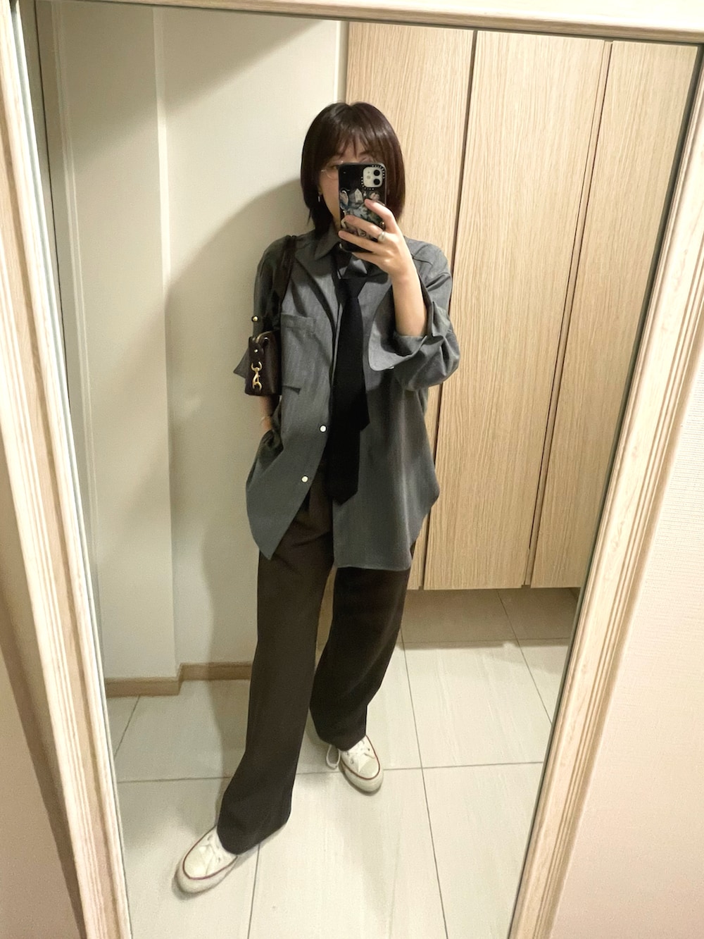 ブラック系のネクタイ、グレー系のシャツ/ブラウス、ブラウン系のスラックスを着用したレディースの秋コーディネートの3枚目の写真